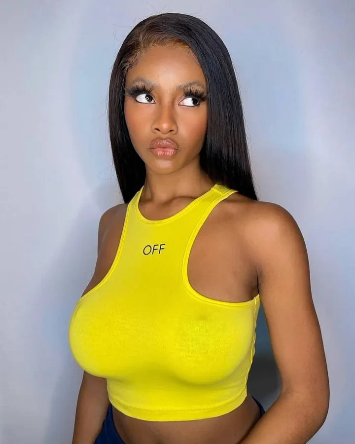 Femme africaine aux cheveux noirs et yeux bleus, portant un haut jaune vif, regardant vers le côté avec un air coquin.
